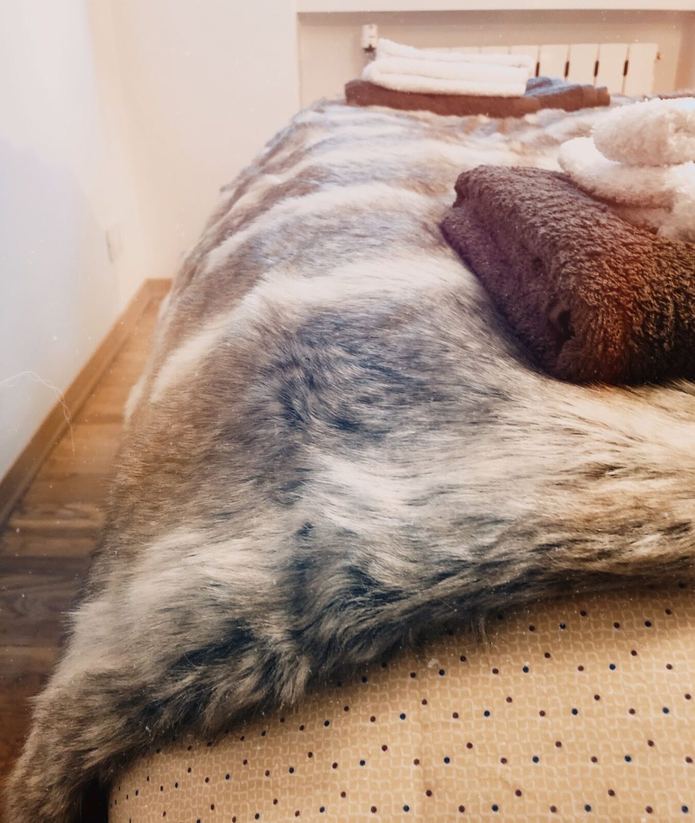 Close-up of folded towels on a bed covered with a textured faux-fur blanket.