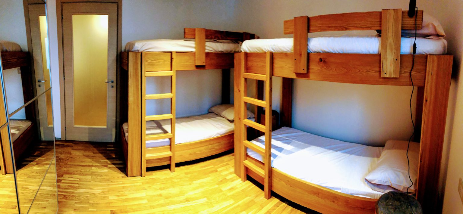 Bedroom filled with multiple wooden bunk beds on a light parquet floor.